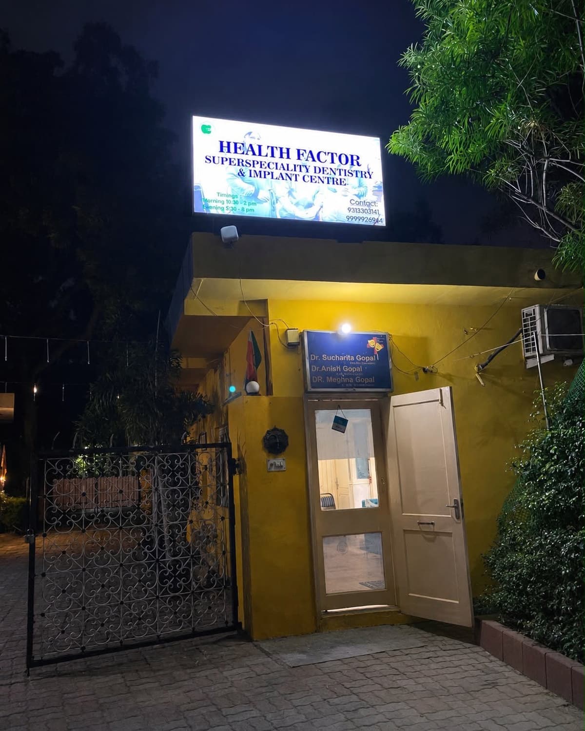 Health Factor Dental Clinic entrance at night, with the lit signboard